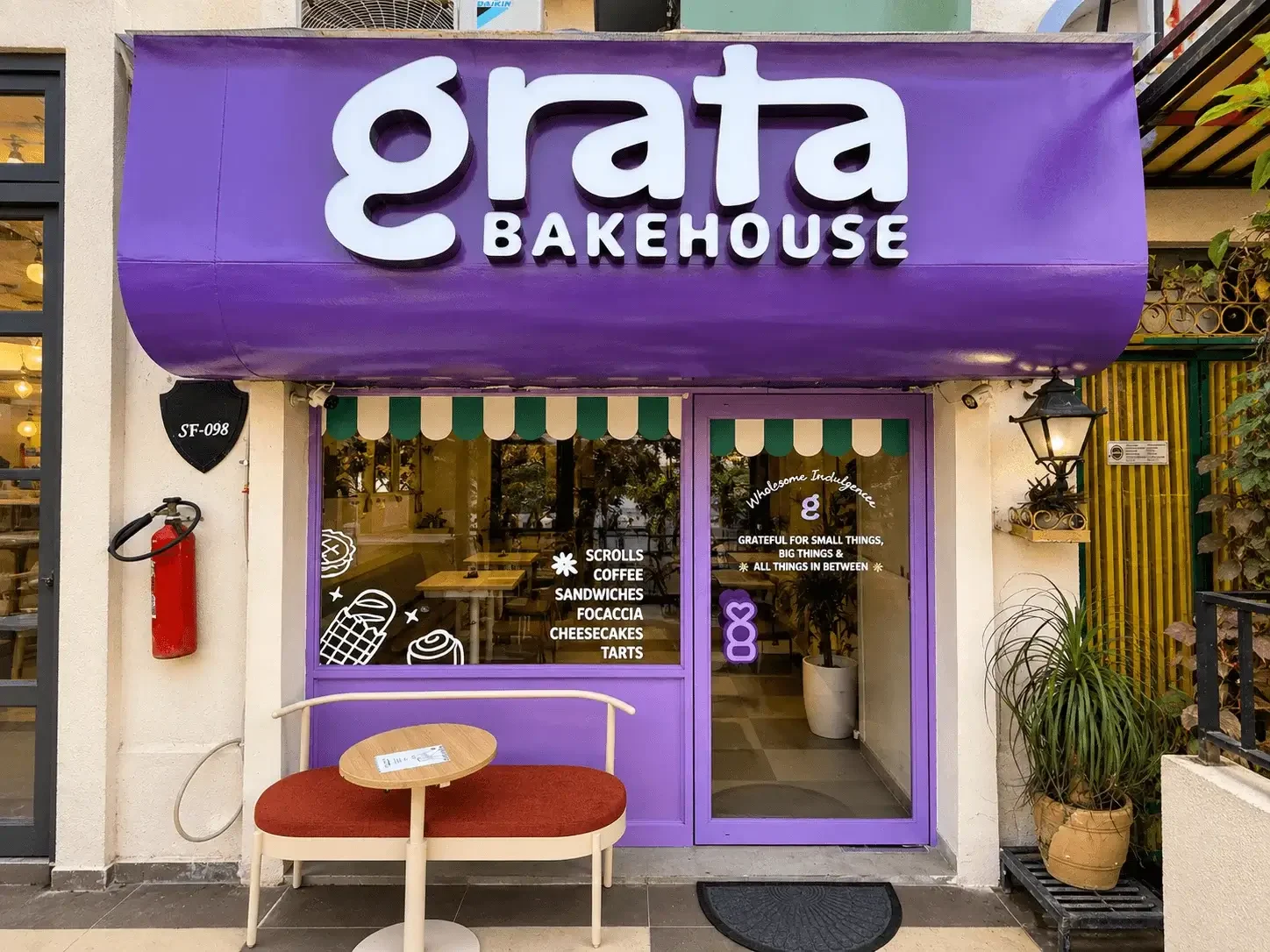 Grata Bakehouse shopfront in Galleria Market: purple facade with a table and chairs outside